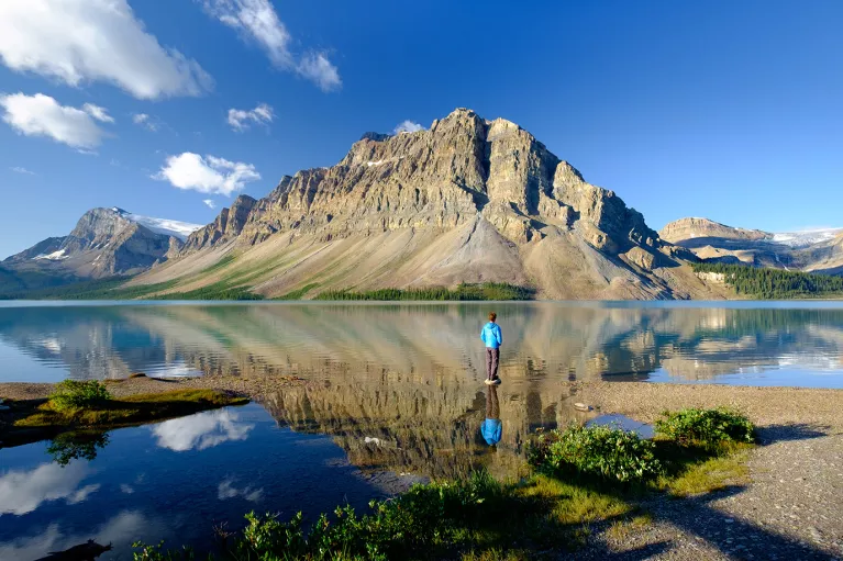 Wide shot of large lake, guest looking towards craggy mountains.