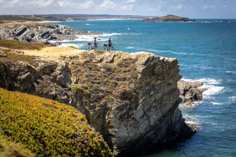 Two bikers resting on a cliff overlooking the sea