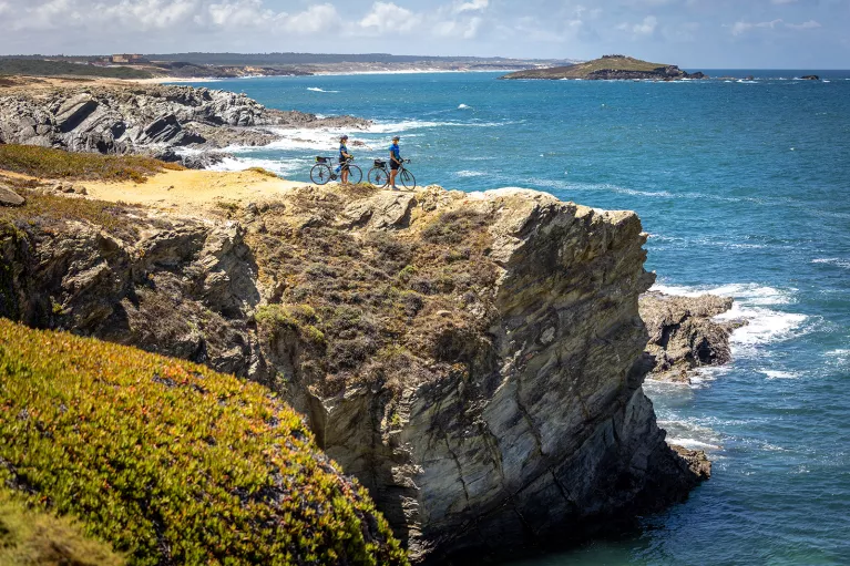Two bikers resting on a cliff overlooking the sea