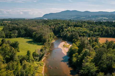 Bird's eye shot of a large river, kayaking guests are visible below.