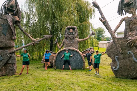 three guests posing with large wire and hay sculptures.