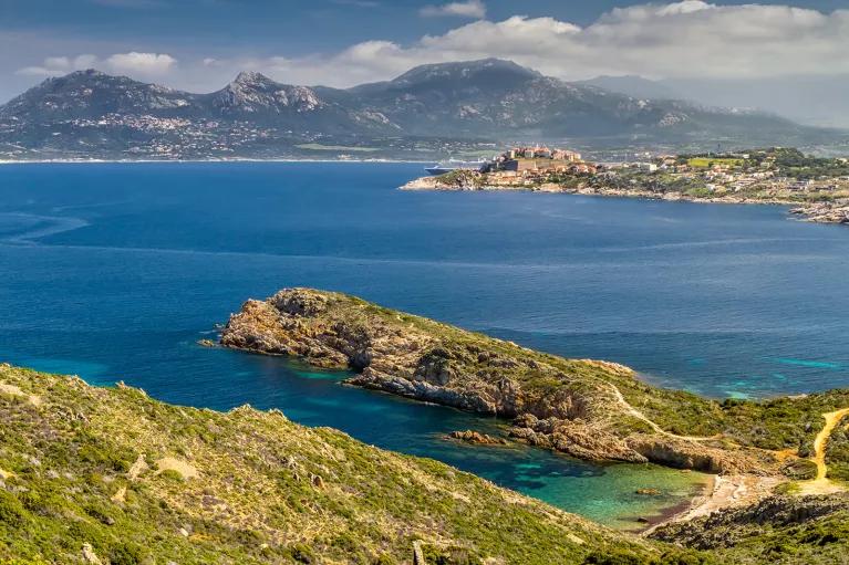 Wide shot of Italian lakeside, large peninsula, hills, coastal town in distance.