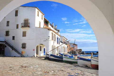 Archway shot of white coastal houses, boats, ocean. 