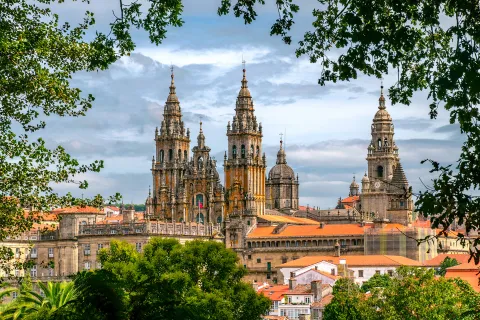 POV shot of Cathedral of Santiago de Compostela, taken from distant treeline.