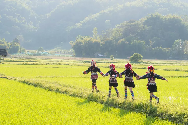 Thai people in traditional clothes running through a green field