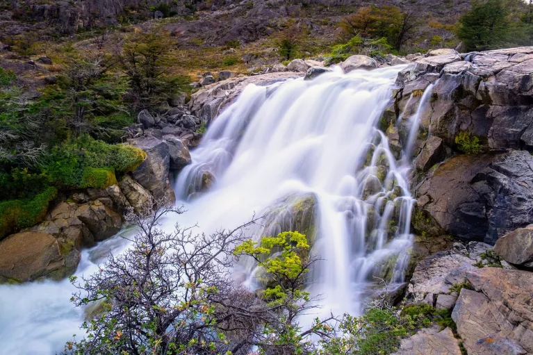 Shot of flowing waterfall, trees, river.