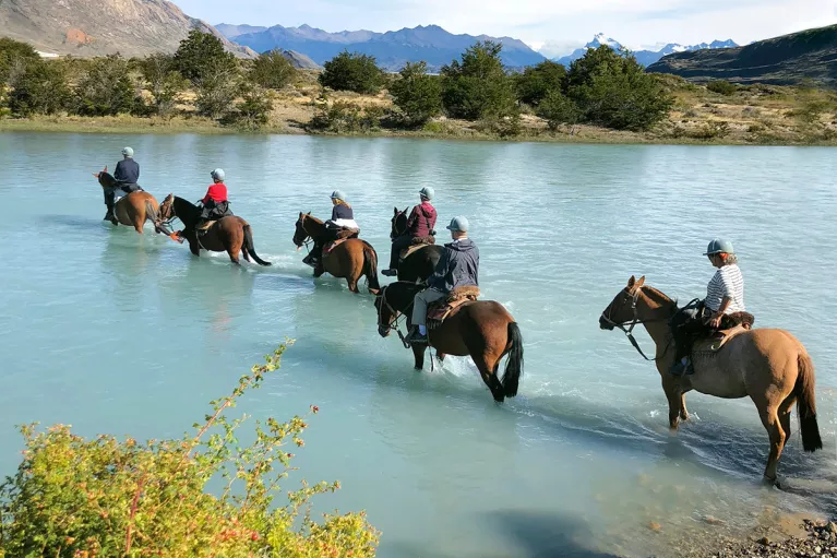 Group of guests on horseback, trekking through cloudy lake.