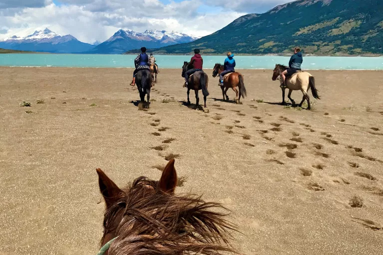 Point of view shot of guests on horseback, heading towards beach.