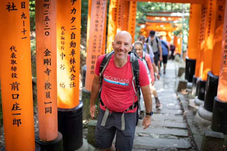 Walking up a hill among orange arches in Japan