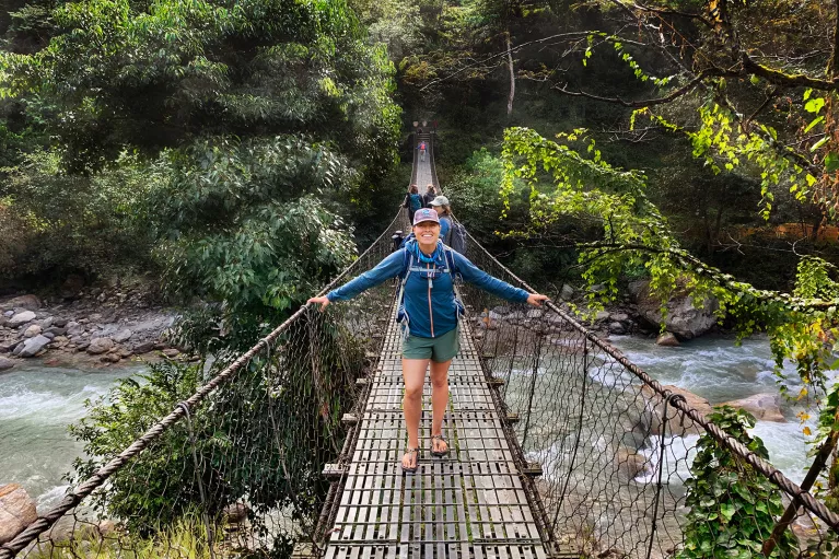 Hiker standing on a bridge over a river in Nepal