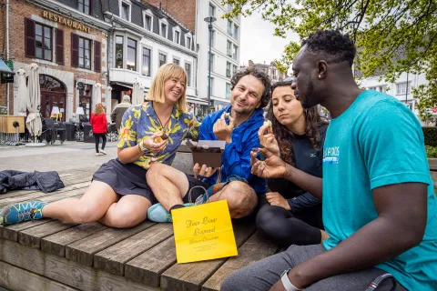 Two men and two women enjoy pastries on a bench