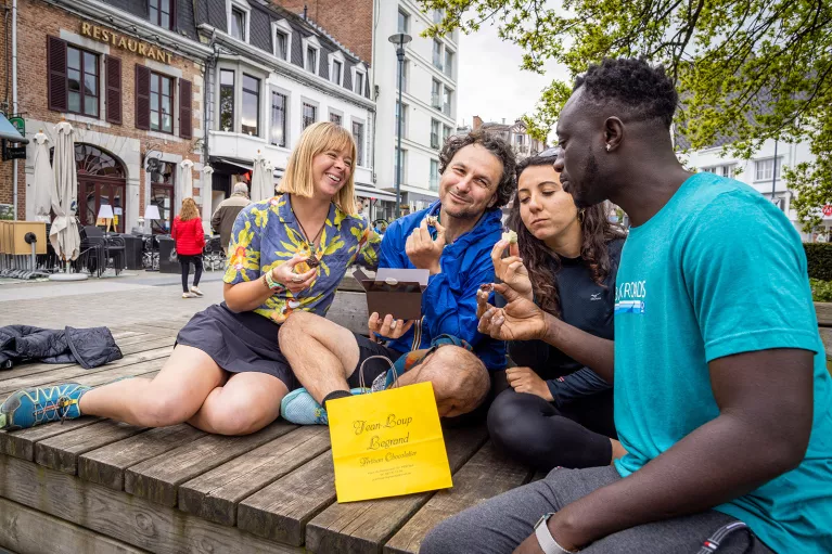 Two men and two women enjoy pastries on a bench