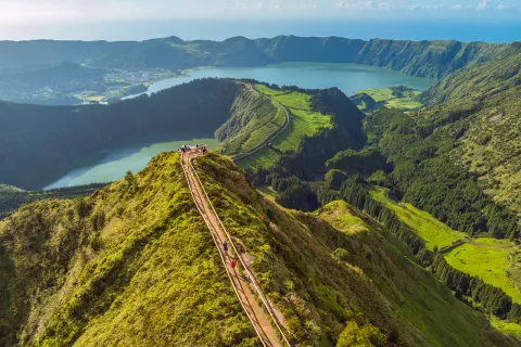 Sky view of a long path that sits on top of a long, grass-covered cliff
