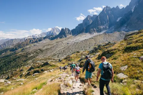 Group of hikers descending down a rocky and grassy hillside