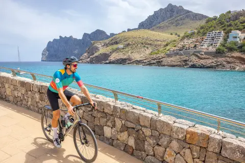 Man biking on a stone path looking out to a lake and a small town
