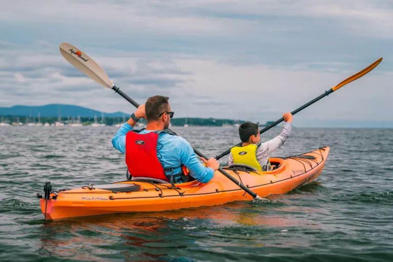 Man and son paddling inside of an orange kayak