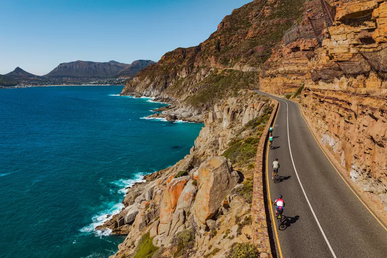 people riding bicycles down a beachfront road