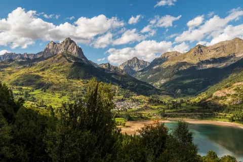 green mountains and lakes below a blue sky with white fluffy clouds
