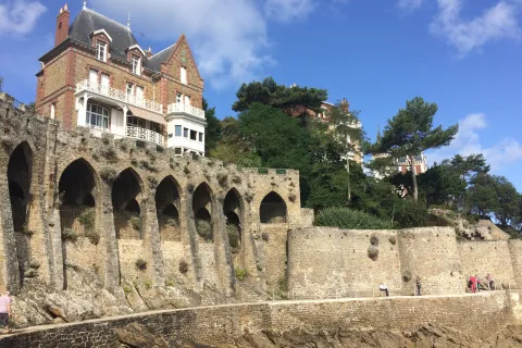 Large house on top of stone castle ruins with a stone pathway on the ground level