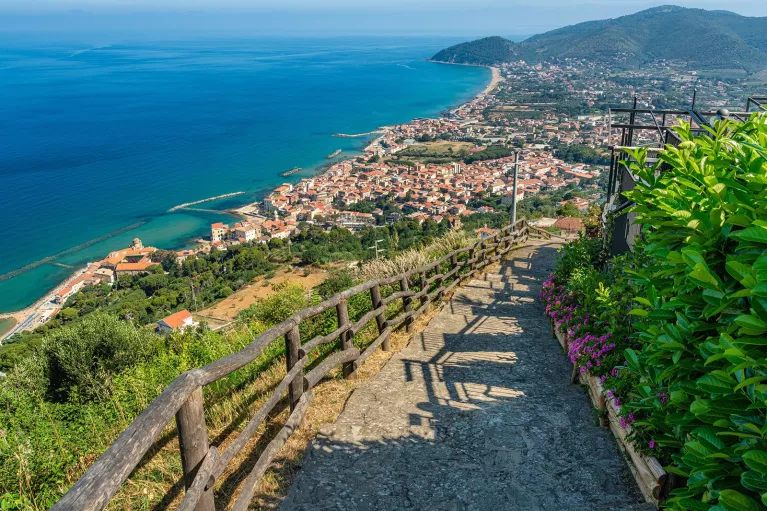 Stone staircase on top of a hill, with views of a beach town in the distance