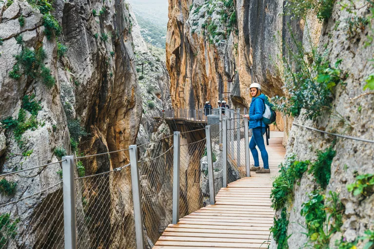 Woman standing on a wooden bridge, between two large cliffs