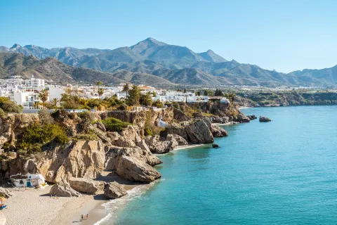 Wide shot view of a town on top of a cliff with the ocean to the right