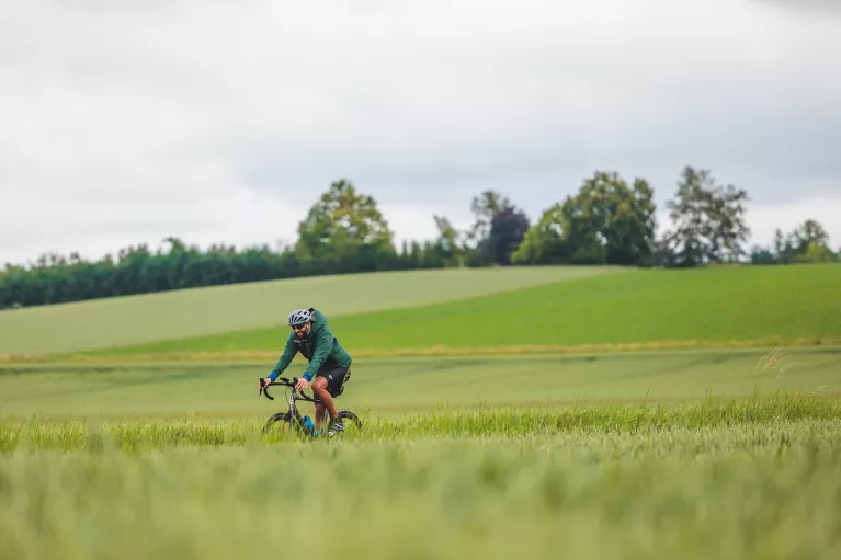 Man riding a bike on a road next to an empty valley of grass