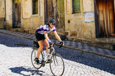 Woman smiling while riding a bike down a road in a town