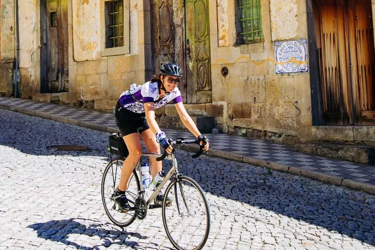 Woman smiling while riding a bike down a road in a town