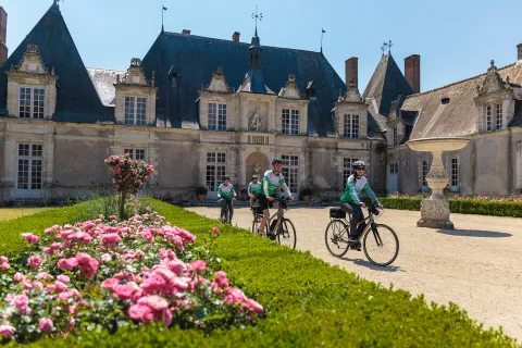 Group of people riding bikes in front of a castle building