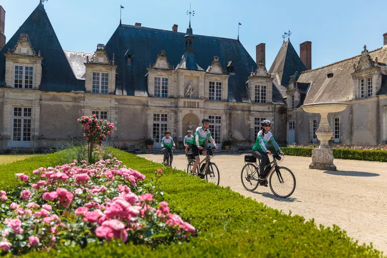 Group of people riding bikes in front of a castle building