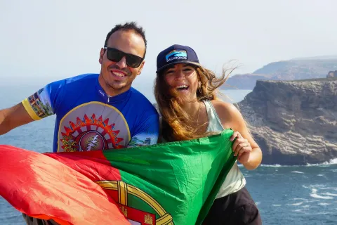 Man and woman smiling while holding up a Portugal flag