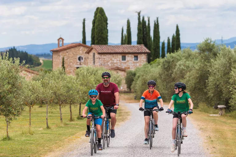 Family riding bikes on a gravel road with a brick church building in the background