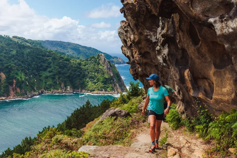 Woman hiking on a dirt trail and looking back towards a river