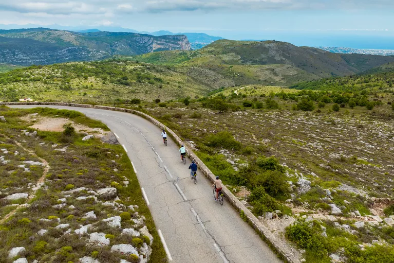 Group of people biking on an empty road, surrounded by a grassy valley