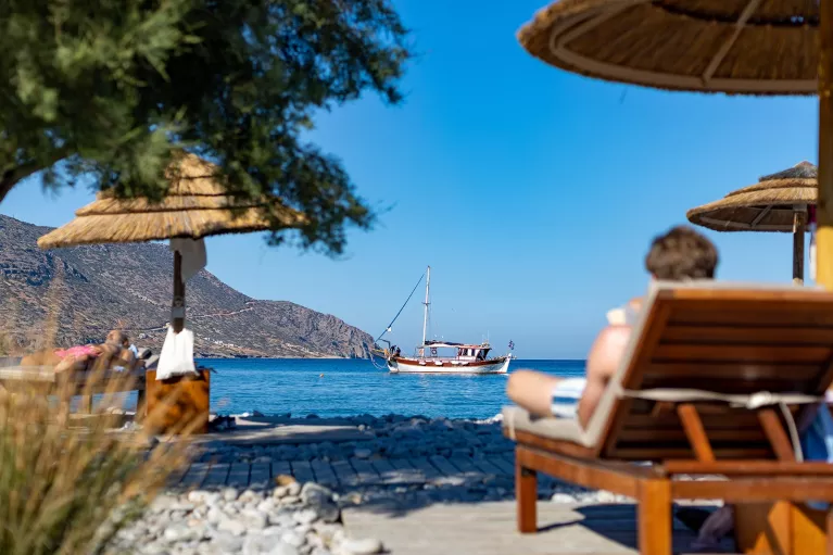 People sitting on reclining chairs by the shore of an ocean