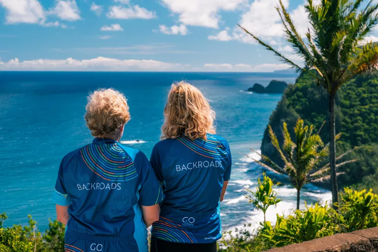 Two women wearing Backroads jerseys, looking out to the ocean
