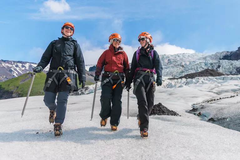Three people wearing snow gear, walking through a icy trail