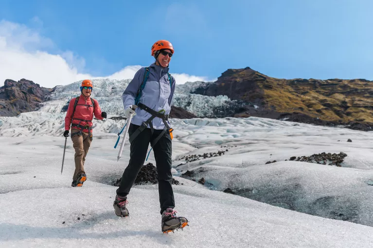 Two hikers walking through a snowy mounds on a trail