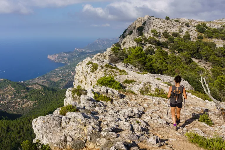 Woman with hiking poles, walking on a large mountain