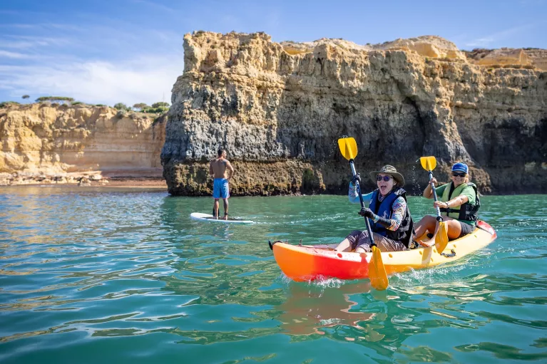 Two women laughing while paddling on a kayak