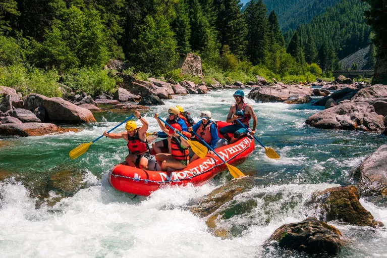 Group of people on a red raft, paddling 