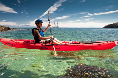 Man paddling on a red kayak in the ocean