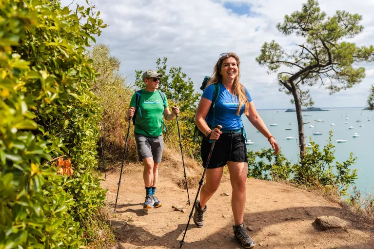 Man and woman smiling while walking through a dirt trail