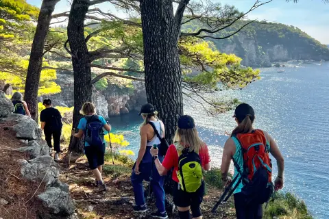 Group of women hiking on a dirt trail by a lake