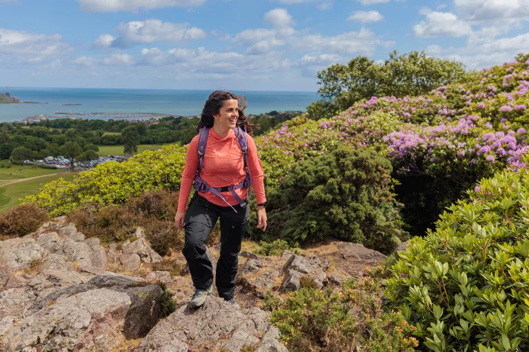 Woman wearing a pink shirt and a backpack, hiking on a rocky hill