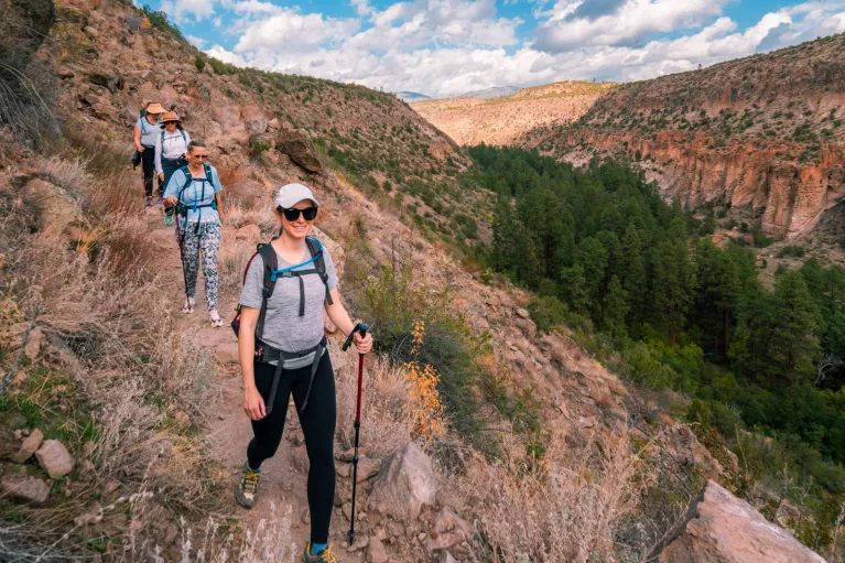 Group of women with walking poles descending a dirt trail