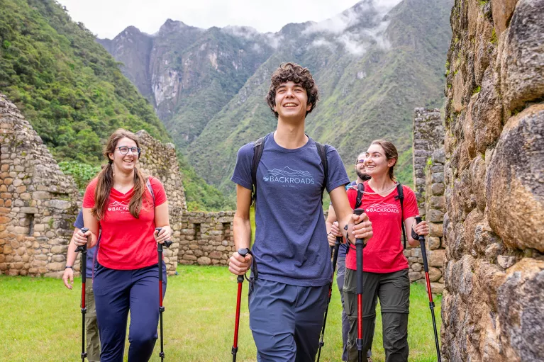 Group of men and women with walking poles, walking through stone ruins