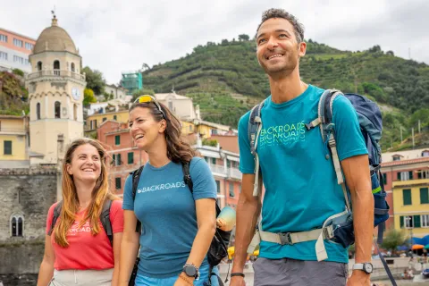 Two women and one man smiling while walking on a boat dock by the water
