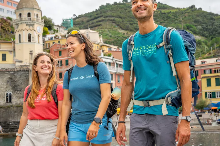 Two women and one man smiling while walking on a boat dock by the water